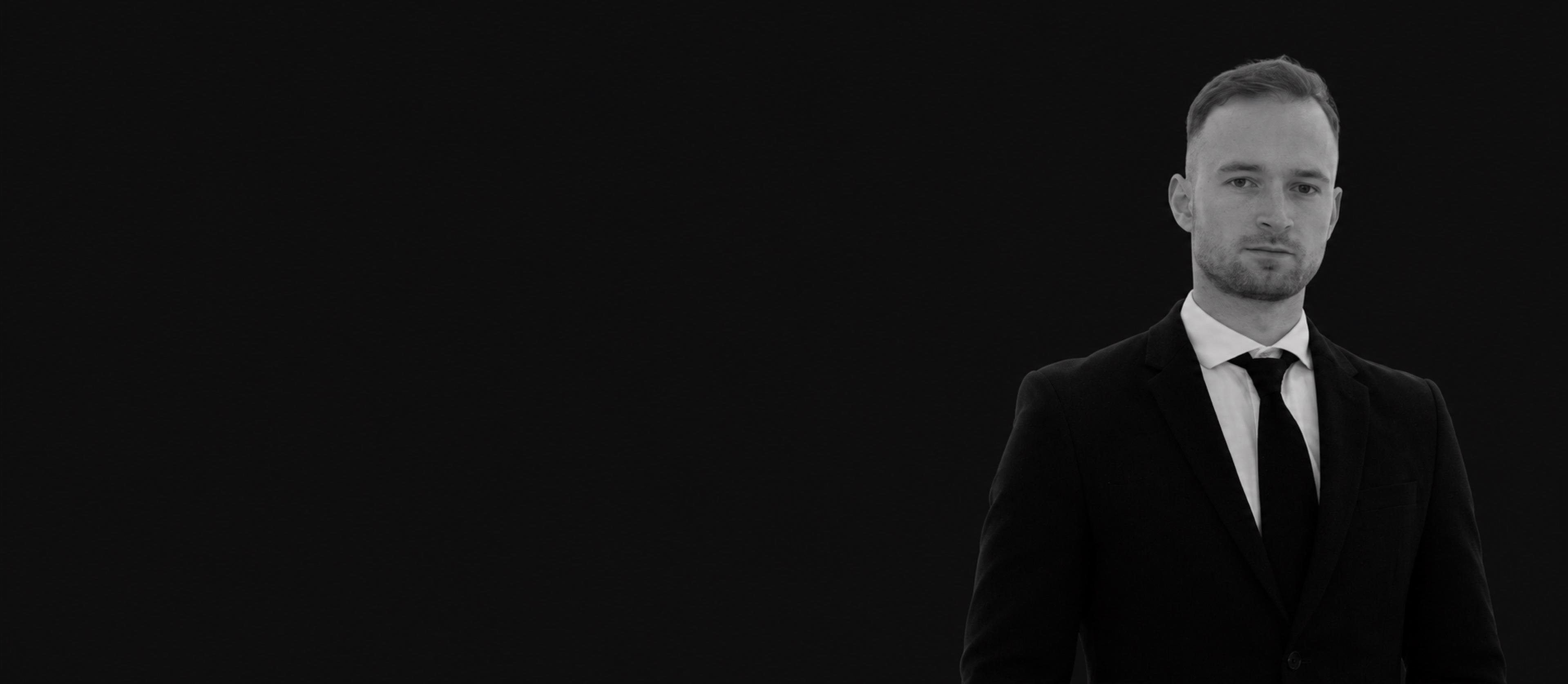 David Demid in a black suit against a dark background